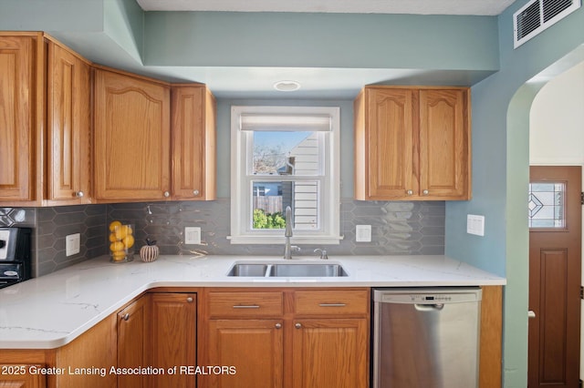kitchen with stainless steel dishwasher, visible vents, arched walkways, a sink, and backsplash
