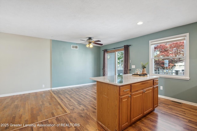 kitchen with light countertops, a ceiling fan, dark wood-type flooring, and visible vents