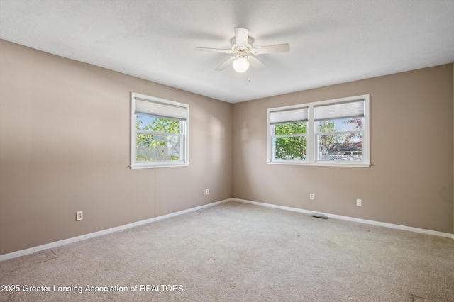 carpeted spare room featuring baseboards, ceiling fan, and visible vents
