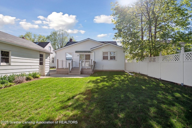 rear view of property featuring a lawn, a deck, and fence