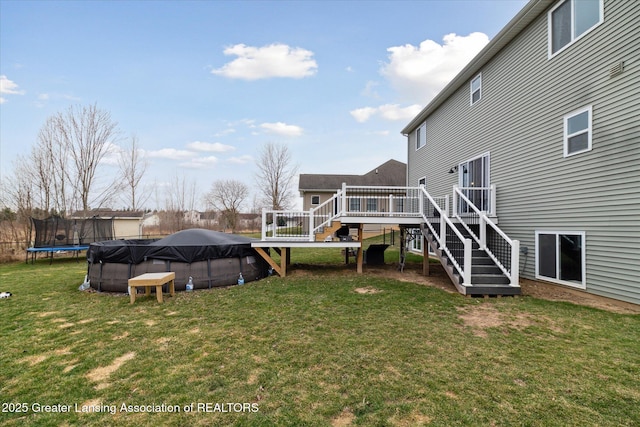 view of yard featuring a trampoline, a deck, a covered pool, and stairway