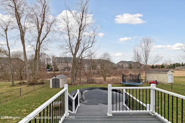 deck featuring a storage shed, a yard, an outdoor structure, and a trampoline