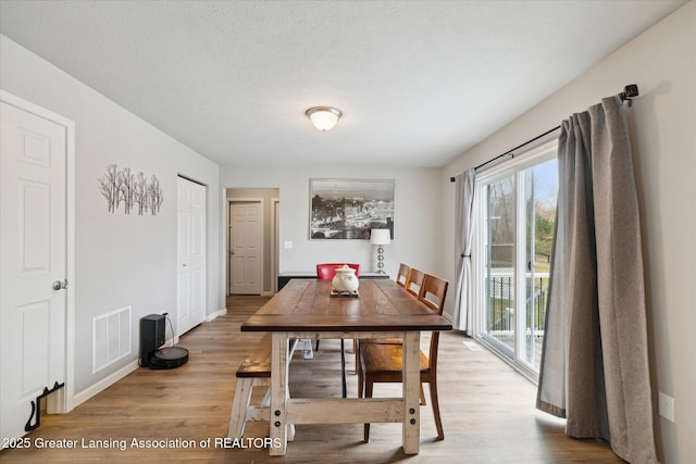 dining area with baseboards, visible vents, and wood finished floors