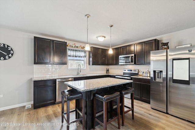 kitchen with backsplash, stainless steel appliances, dark brown cabinetry, and a sink