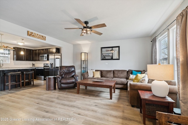 living area featuring light wood-style floors and a ceiling fan