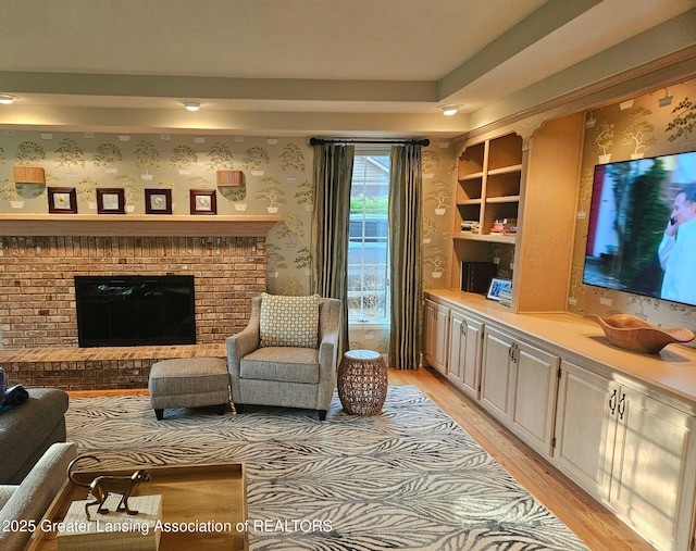 living room with a fireplace, wallpapered walls, and light wood-type flooring