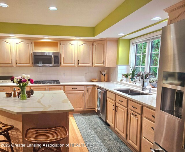 kitchen featuring light brown cabinetry, light stone countertops, appliances with stainless steel finishes, a sink, and recessed lighting