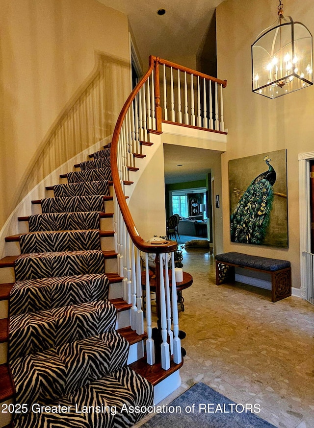 staircase with an inviting chandelier and a high ceiling