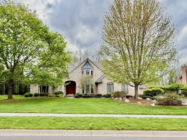view of front facade with brick siding and a front yard