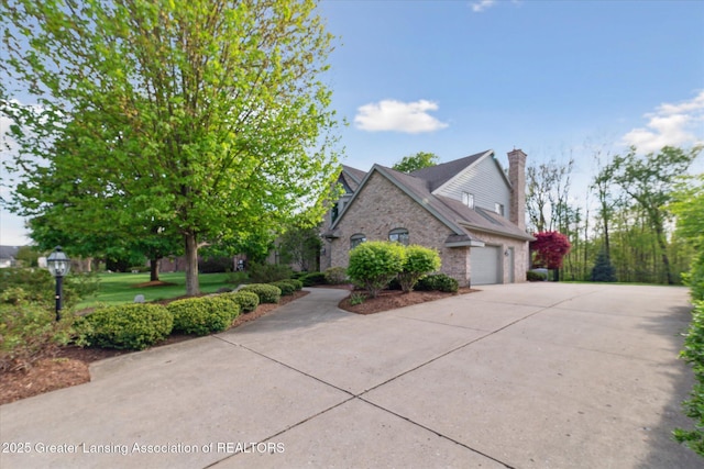 3641 Beech Tree Ln, Okemos, MI 48864 - view of front of home featuring concrete driveway, a garage, a chimney, and stone siding