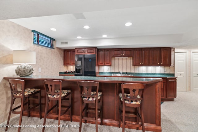3641 Beech Tree Ln, Okemos, MI 48864 - kitchen with black fridge, dark countertops, a sink, a kitchen bar, and recessed lighting