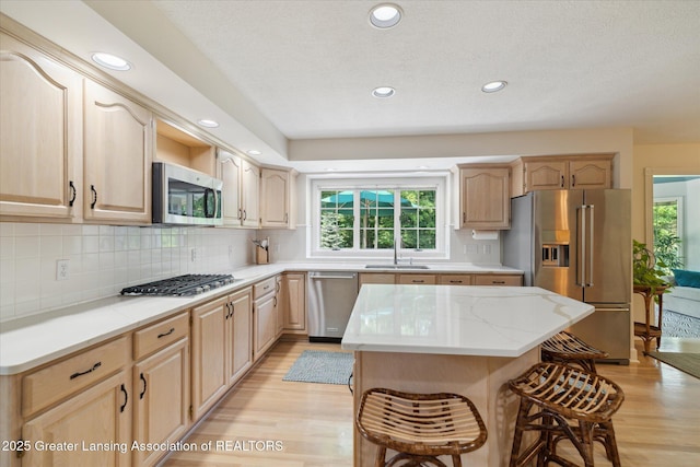 3641 Beech Tree Ln, Okemos, MI 48864 - kitchen featuring stainless steel appliances, a breakfast bar area, light wood finished floors, light brown cabinetry, and recessed lighting
