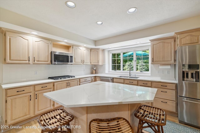 3641 Beech Tree Ln, Okemos, MI 48864 - kitchen with appliances with stainless steel finishes, light brown cabinets, a kitchen breakfast bar, decorative backsplash, and a center island