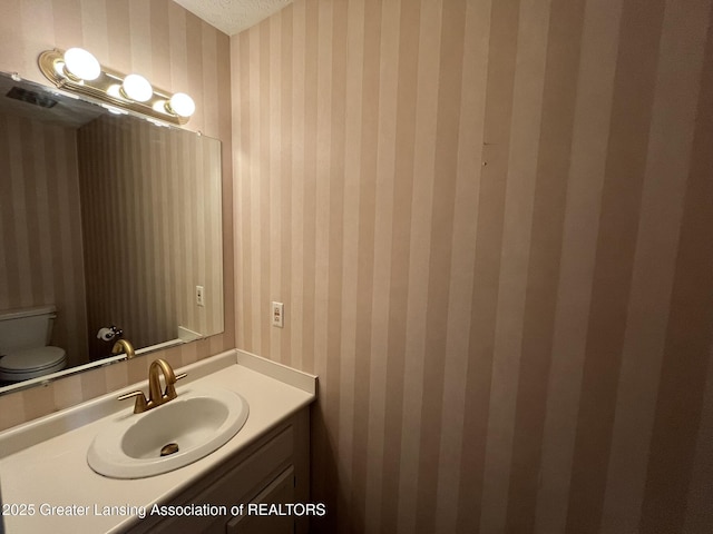 1425 E Lakeside Dr, East Lansing, MI 48823 - bathroom featuring vanity, toilet, and wallpapered walls