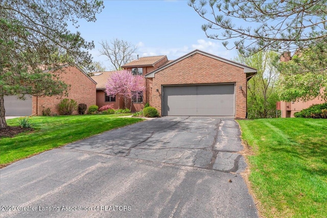 2454 Emerald Lake Dr, East Lansing, MI 48823 - view of front facade with brick siding, a garage, and aphalt driveway