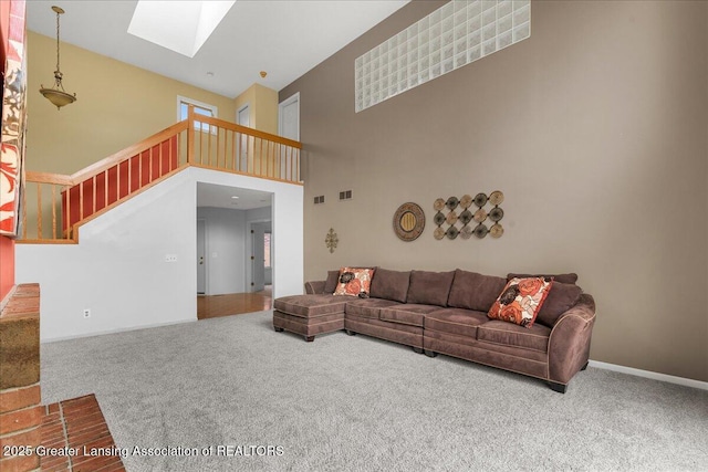 2454 Emerald Lake Dr, East Lansing, MI 48823 - carpeted living area with visible vents, stairs, a towering ceiling, baseboards, and a skylight