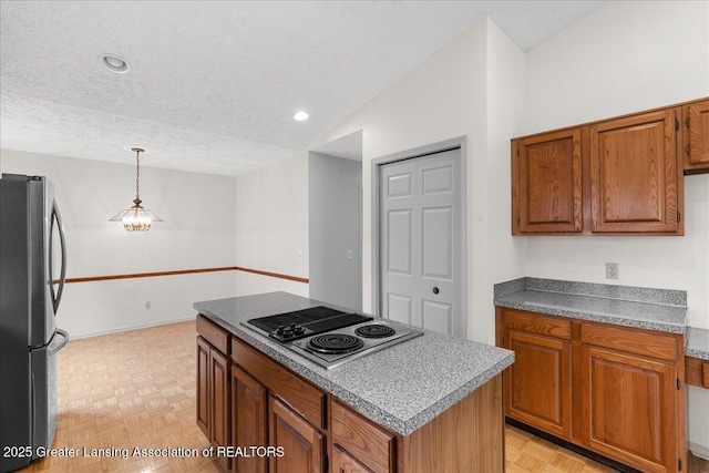 2454 Emerald Lake Dr, East Lansing, MI 48823 - kitchen with stovetop with downdraft, freestanding refrigerator, a textured ceiling, and brown cabinets