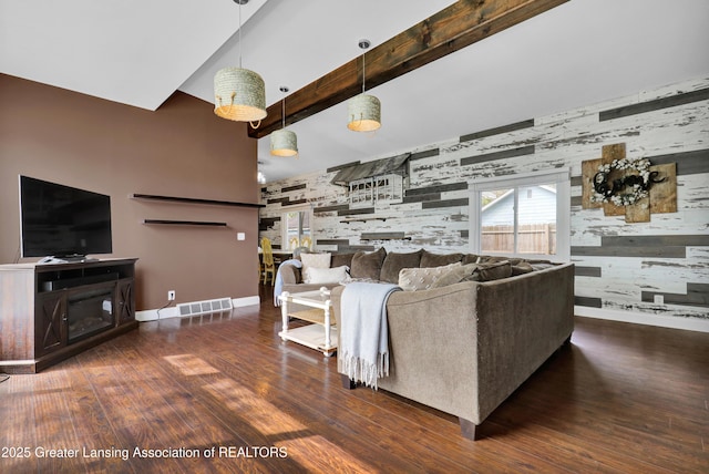 living room with visible vents, a fireplace, wood finished floors, baseboards, and an accent wall
