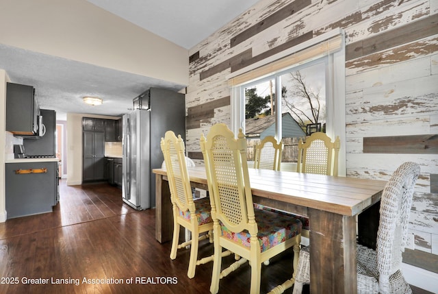 dining room with wood walls and dark wood-style floors