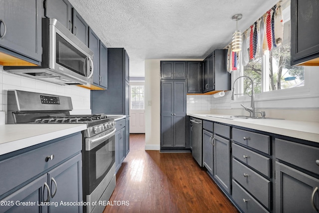 kitchen with dark wood-type flooring, a sink, light countertops, and stainless steel appliances