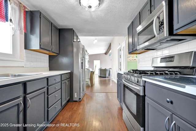 kitchen featuring backsplash, stainless steel appliances, and gray cabinetry