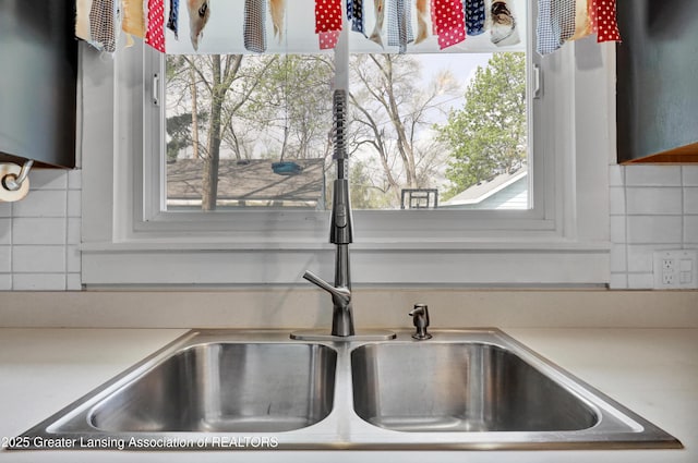 interior details featuring light countertops, a sink, and tasteful backsplash