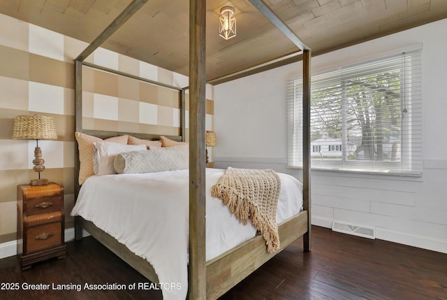 bedroom with baseboards, wood finished floors, and visible vents