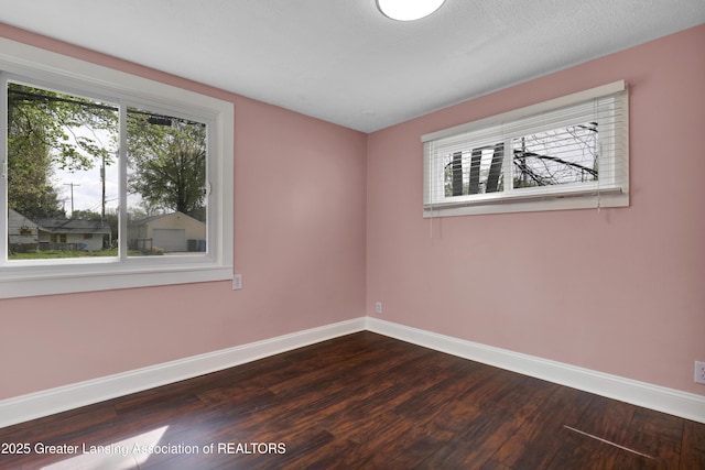 unfurnished room featuring baseboards and dark wood finished floors