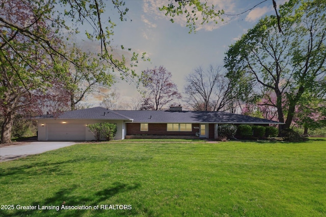 ranch-style home featuring an attached garage, driveway, a chimney, and a front lawn
