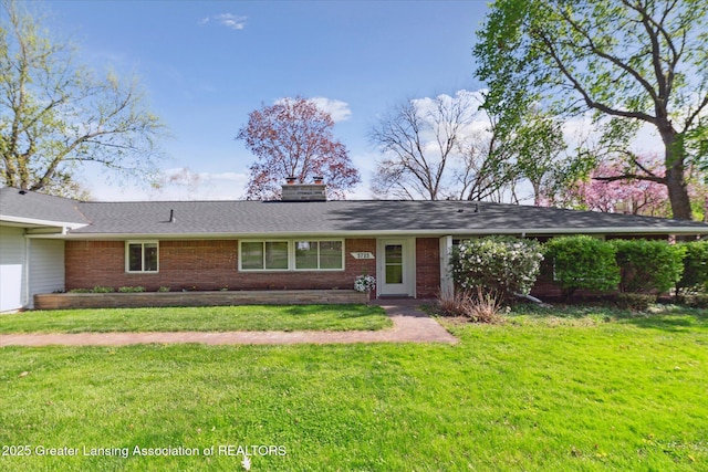ranch-style home with brick siding, a front lawn, and a chimney