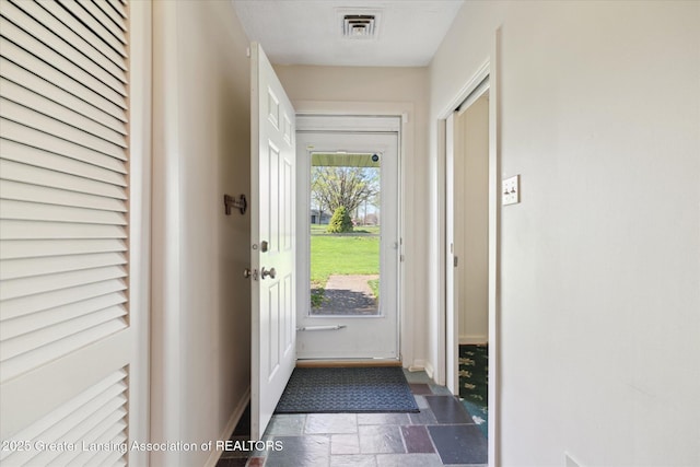 doorway featuring visible vents, baseboards, and stone tile flooring