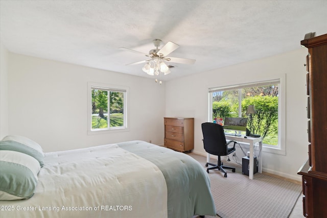 carpeted bedroom featuring baseboards, ceiling fan, and multiple windows