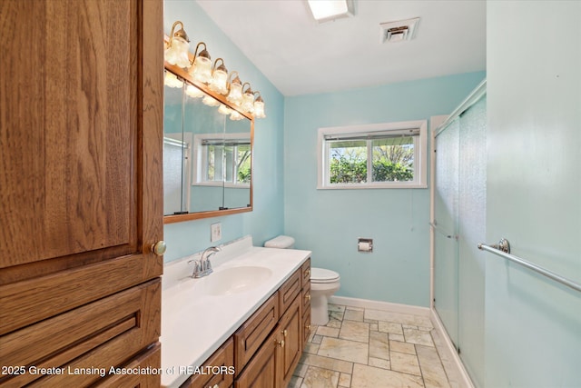 full bathroom with vanity, baseboards, a shower stall, and stone tile flooring