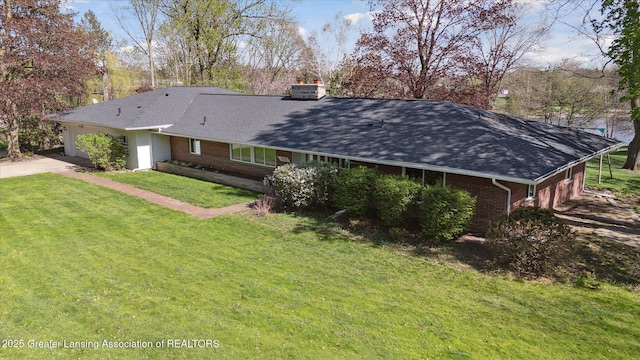 exterior space with a garage, roof with shingles, brick siding, concrete driveway, and a yard