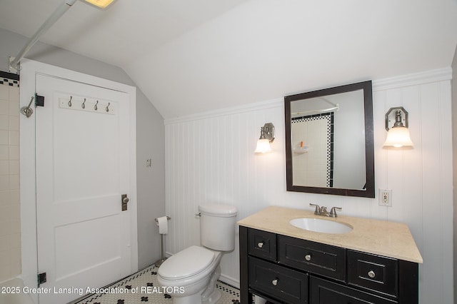 bathroom featuring vanity, vaulted ceiling, toilet, and tiled shower