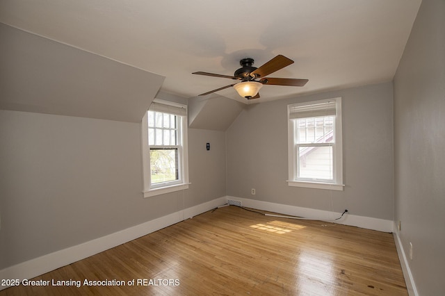 additional living space featuring baseboards, plenty of natural light, a ceiling fan, and light wood-type flooring