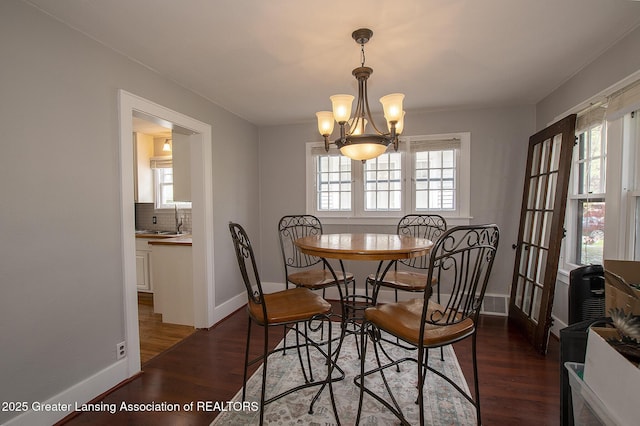 dining area featuring an inviting chandelier, baseboards, wood finished floors, and a healthy amount of sunlight