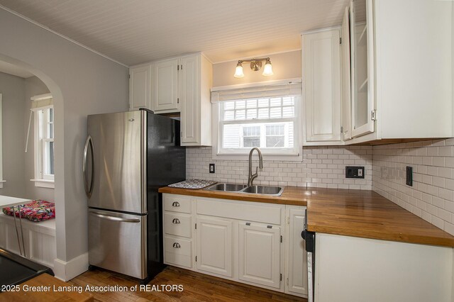 kitchen featuring freestanding refrigerator, a sink, butcher block counters, and white cabinets