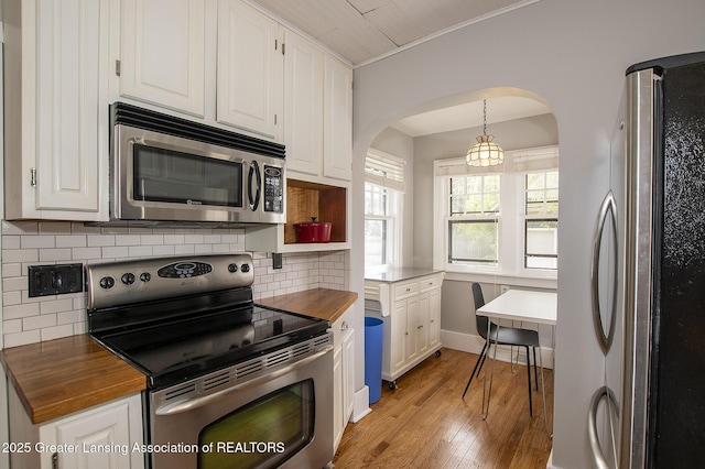 kitchen with arched walkways, appliances with stainless steel finishes, and white cabinets