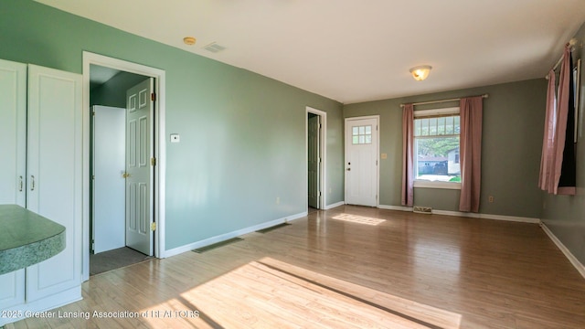 interior space featuring baseboards, visible vents, and wood finished floors