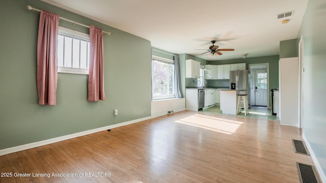 unfurnished living room with a ceiling fan, baseboards, visible vents, and light wood-type flooring