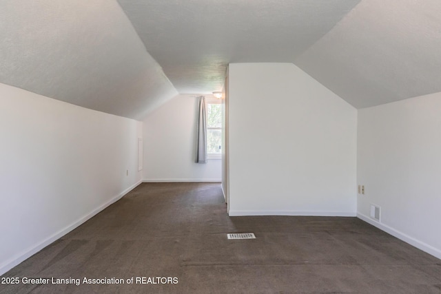 bonus room with visible vents, dark carpet, and lofted ceiling
