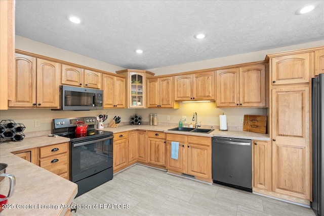 kitchen with a sink, light countertops, black appliances, glass insert cabinets, and recessed lighting
