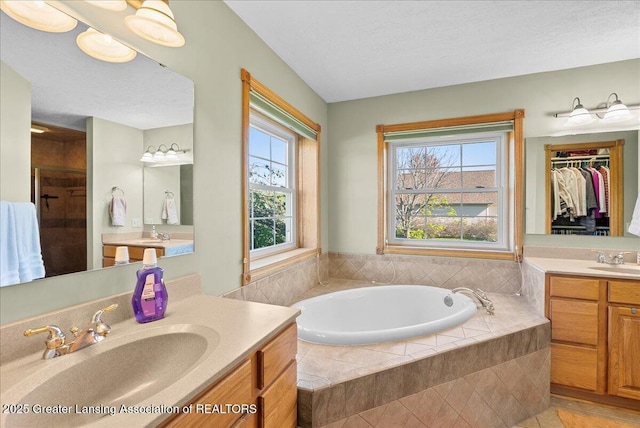 full bath with a sink, a garden tub, a stall shower, and two vanities