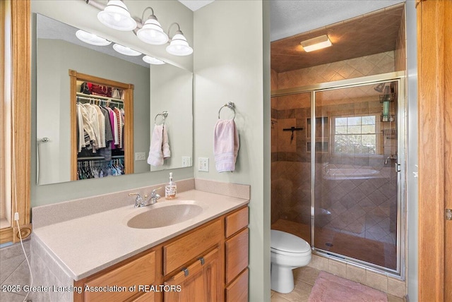 full bathroom featuring vanity, toilet, a walk in closet, tile patterned floors, and a shower stall