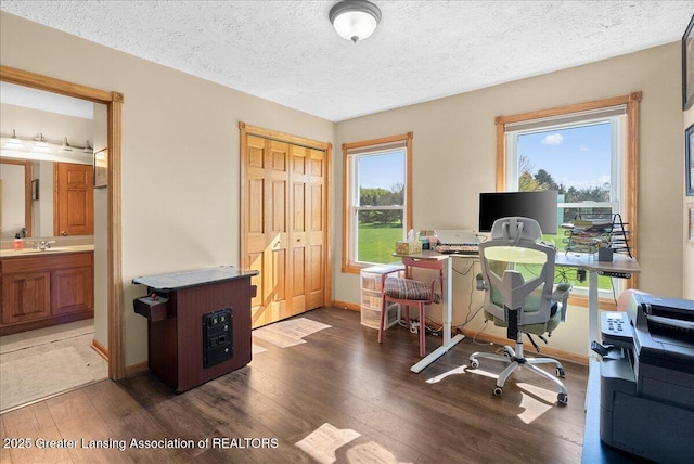 office with a sink, baseboards, a textured ceiling, and wood finished floors