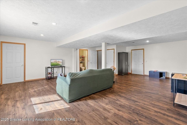 living room with baseboards, visible vents, a textured ceiling, and wood finished floors