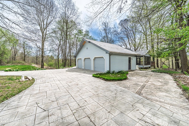 exterior space with a sunroom, an outbuilding, and driveway
