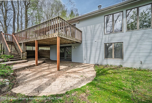 rear view of property with stairs, a lawn, a wooden deck, and a patio