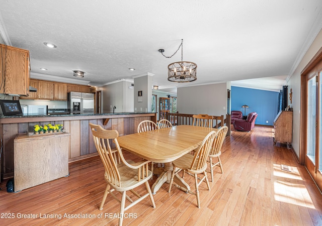 dining room featuring light wood-type flooring, crown molding, and a wealth of natural light